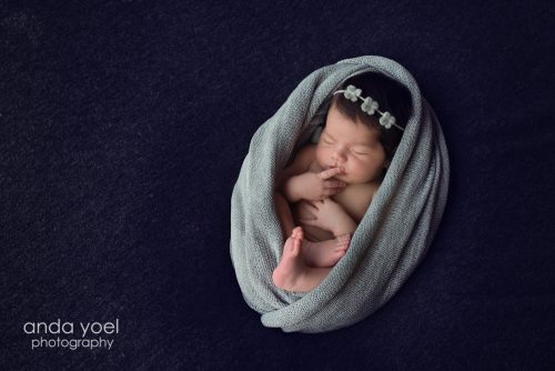 תינוקת בעיטוף אפור וסרט פרחוני - צילומי ניו בורן בסטודיו אנדה יואל