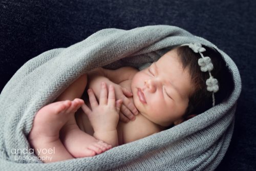 תינוקת בעיטוף אפור וסרט פרחוני - צילומי ניו בורן בסטודיו אנדה יואל