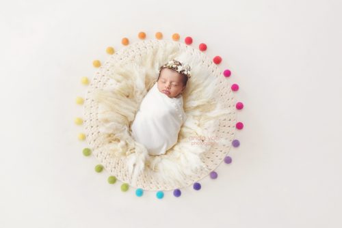 ניובורן בעיטוף לבן בין כדורי צמר צבעוניים - צילומי ניובורן בסטודיו אנדה יואל