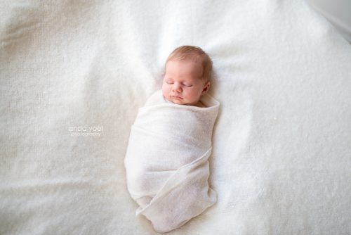 צילומי ניובורן תינוקת עטופה בד רך בצבע לבן - סטודיו אנדה יואל